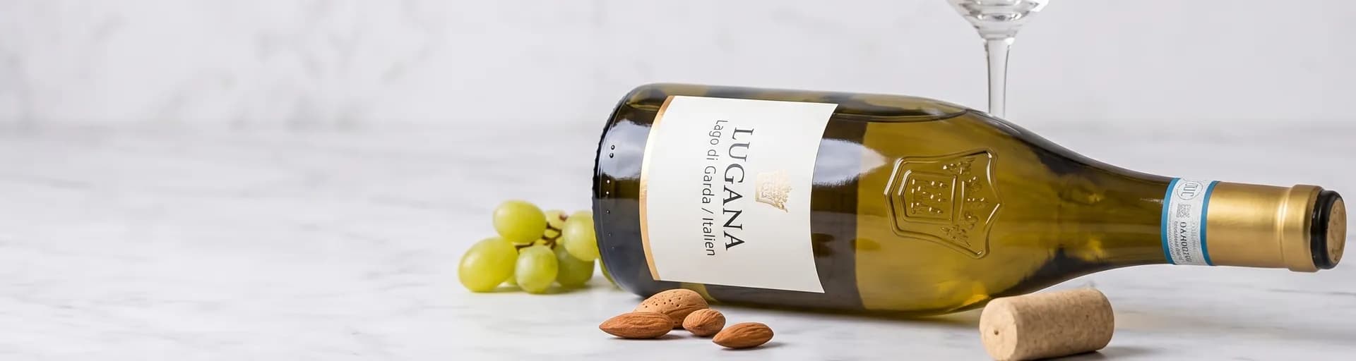 Lugana Flasche liegend mit Weintrauben